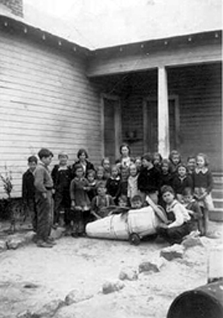 Unidentified class of children and teacher at Brushey Creek School with what appears to be homemade toy airplane.