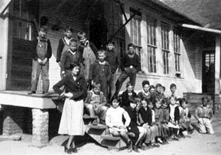 Unidentified class of children and teacher on porch and steps at Brushey Creek School.