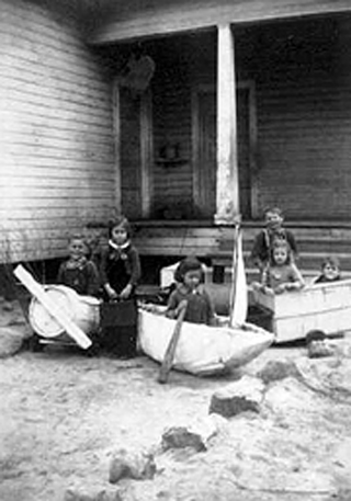 Six unidentified children at Brushey Creek School in toy airplane, boat and cart that appear to be homemade.